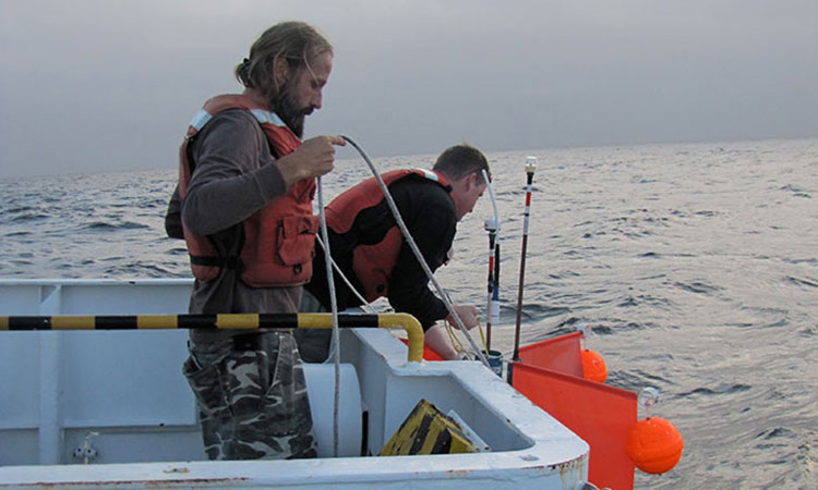 Dr. Kay Bidle collecting a sample aboard a research vessel